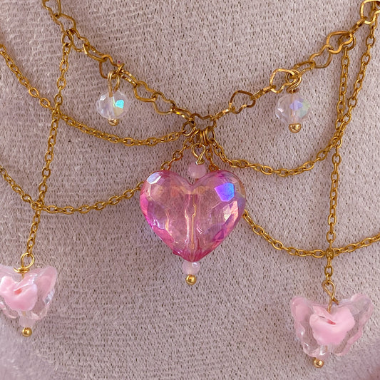 Necklace with pink heart pendant and bear charms on a textured surface