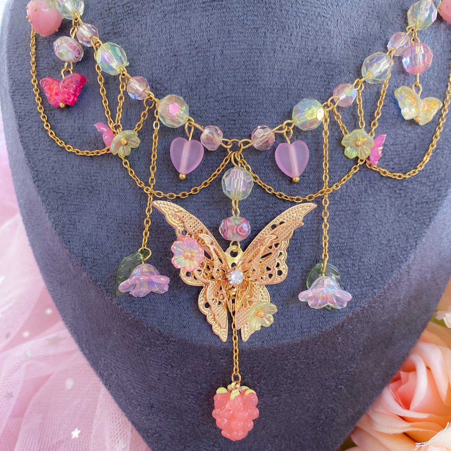 Necklace with butterfly pendant and colorful beads on a mannequin head with pink roses.