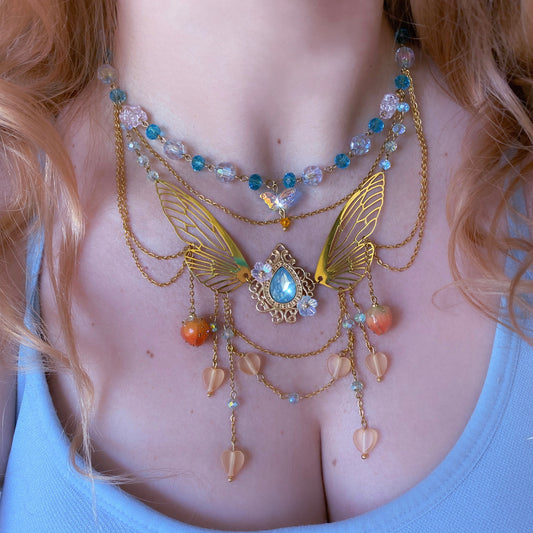 Necklace with butterfly design and beads on a person wearing a blue top
