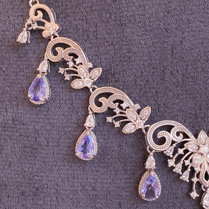 Ornate silver necklace with purple gemstones on a gray background